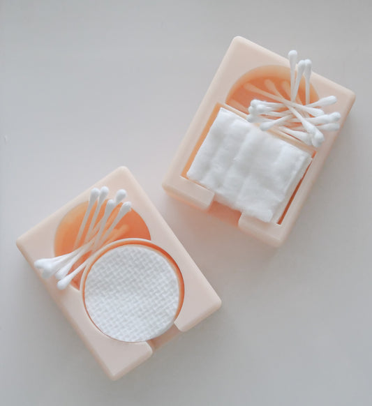 The Hello Cutters Round Cotton Holder Duo, in beige, organizes cotton pads and Q-tips—one holder contains round pads, while the other holds square pads with Q-tips on top—displayed on a white surface.
