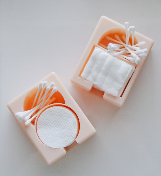 The Hello Cutters Rectangle Cotton Holder Duo features two peach containers: one for round cotton pads, the other for square ones, each topped with neatly arranged Q-tips. Their minimalist design stands out against a white backdrop—ideal for 3D print fans.