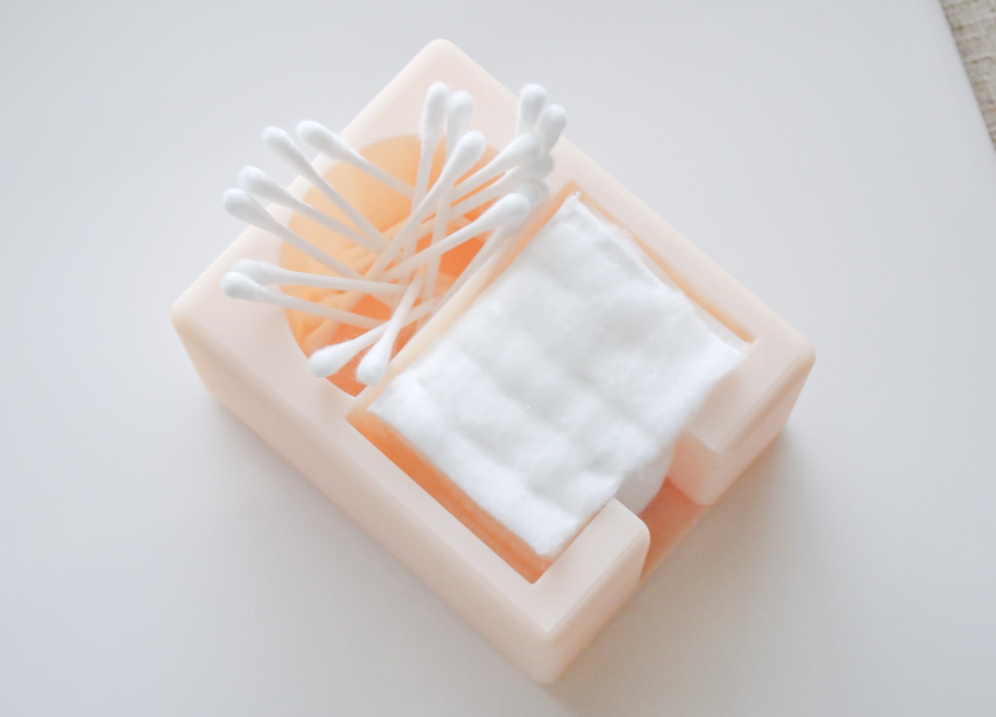 The Hello Cutters Rectangle Cotton Holder Duo, a beige plastic organizer, neatly stores Q-tips and cotton pads on a light surface.