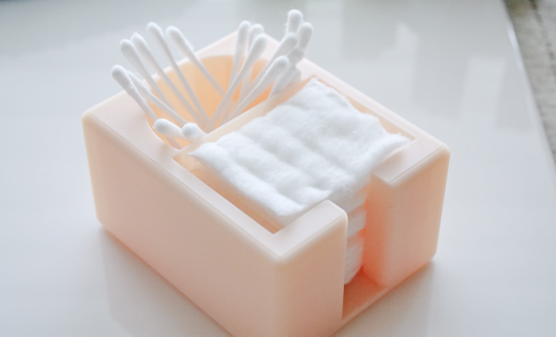 The Hello Cutters Rectangle Cotton Holder Duo, in beige plastic, neatly stores stacked cotton pads and upright Q-tips on a clean white surface.